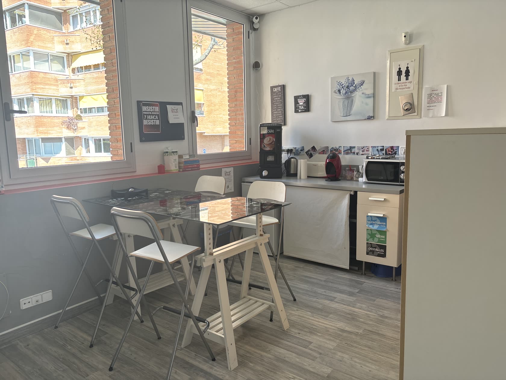 Office amb taula alta, tamborets i racó de cafè al coworking