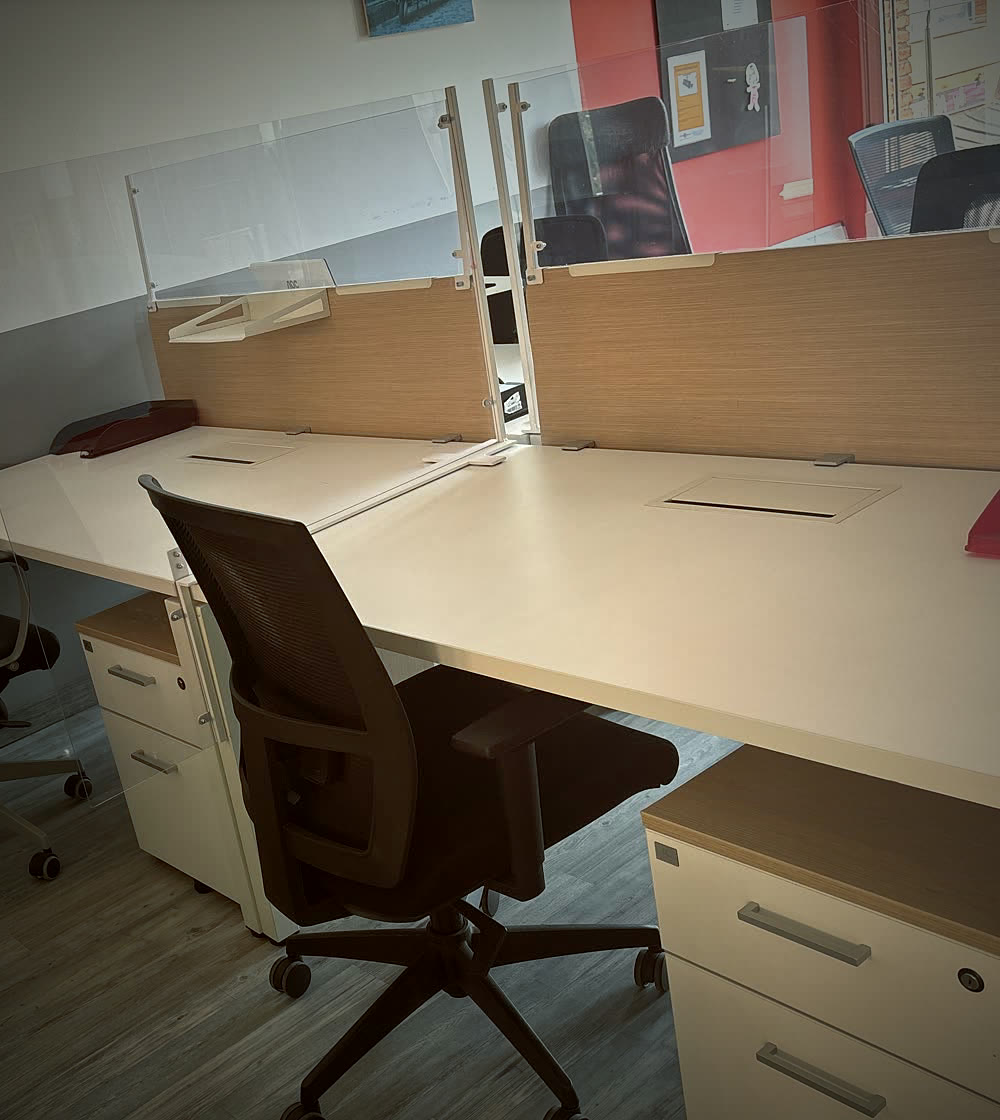 Llocs de treball amb mampares i paret vermella al coworking CoActiva't (fotografia editada)