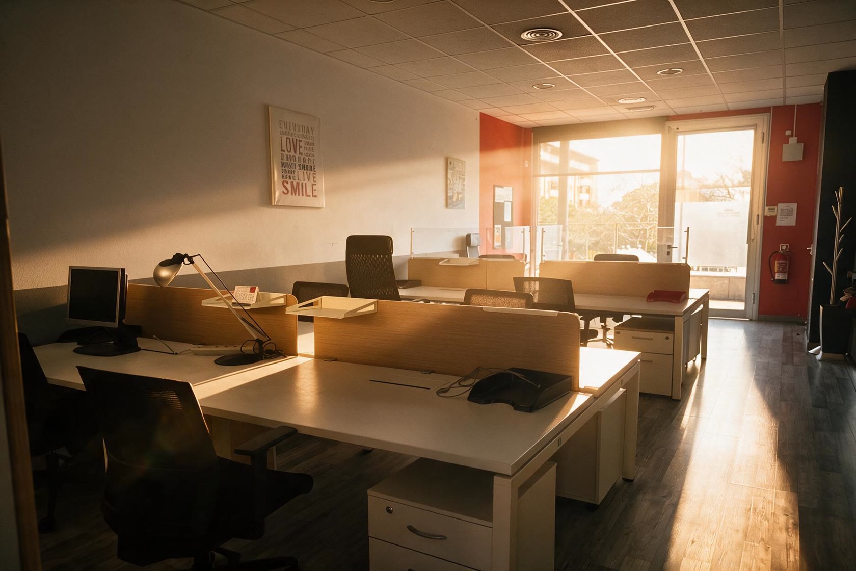 Open space del coworking CoActiva't amb llum daurada de tarda entrant per la cristallera